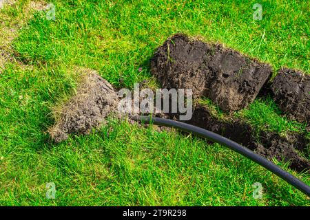 Un fossé creusé dans la pelouse pour la pose de tuyaux et l'installation d'irrigation. Sol sous pelouse verte et système de racines d'herbe Banque D'Images