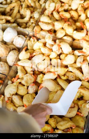Vue rapprochée verticale de la main blanche prenant des crevettes précuites dans un supermarché pour le dîner. Banque D'Images