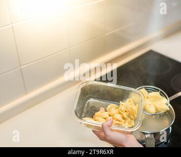 Vue de dessus des boulettes de pâtes tortellini au fromage bouillies dans l'eau et versées dans un récipient en verre Banque D'Images