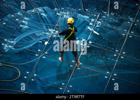 Doha, Qatar - 10 novembre 2023 : le nettoyeur de vitres travaille sur la façade d'un immeuble de grande hauteur dans la baie ouest de Doha Banque D'Images