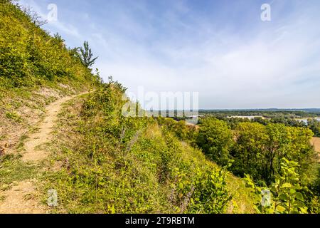 Sentier de randonnée sur versant de montagne, végétation sauvage luxuriante et arbres, rivière Maas et horizon en arrière-plan, réserve naturelle du Thier de Lanaye en partie belge o Banque D'Images