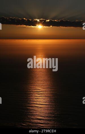 Le soleil couchant jette un coup d'œil derrière les nuages au-dessus de l'océan Altantic. Banque D'Images