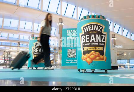 USAGE ÉDITORIAL SEULS les passagers à Heathrow passent par le Heinz Duty Freanz Airside Experience, où les vacanciers peuvent récupérer une boîte de haricots gratuite à emporter lors de leur voyage. Date de la photo : lundi 27 novembre 2023. Banque D'Images