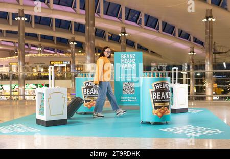 USAGE ÉDITORIAL SEULS les passagers à Heathrow passent par le Heinz Duty Freanz Airside Experience, où les vacanciers peuvent récupérer une boîte de haricots gratuite à emporter lors de leur voyage. Date de la photo : lundi 27 novembre 2023. Banque D'Images