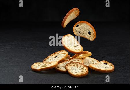 Craquelins bruschetta tombant, croûtons de pain rond isolés sur fond noir Banque D'Images