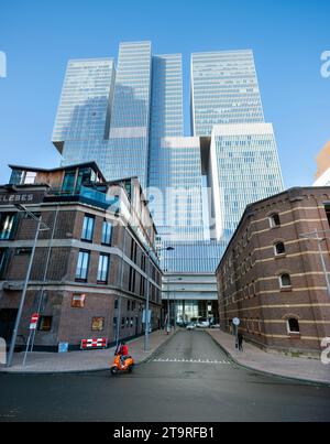 rotterdam, pays-bas, 25 novembre 2023 : cyclomoteur près de bâtiments anciens et gratte-ciel par les architectes oma à rotterdam Banque D'Images