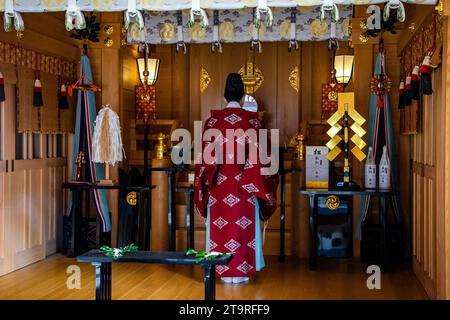 Une jeune femme portant un kimono rouge vif dans une chambre japonaise traditionnelle. Banque D'Images