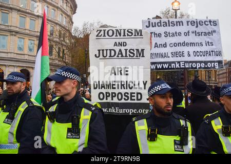 Londres, Royaume-Uni. 26 novembre 2023. Des policiers entourent des Juifs ultra-orthodoxes anti-sionistes et pro-palestiniens tenant une pancarte qui déclare "le sionisme et le judaïsme sont diamétralement opposés" qui organisent une contre-manifestation à Trafalgar Square. Des milliers de manifestants pro-israéliens ont défilé dans le centre de Londres contre l’antisémitisme et ont appelé à la libération des otages israéliens détenus par le Hamas à Gaza. Crédit : SOPA Images Limited/Alamy Live News Banque D'Images