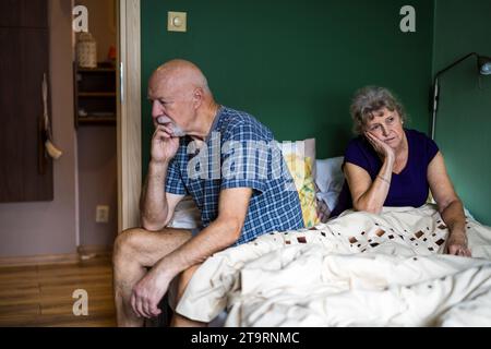 Couple senior est assis sur le lit ayant un problème relationnel Banque D'Images