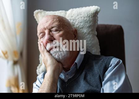 Homme senior dormant dans un fauteuil à la maison Banque D'Images
