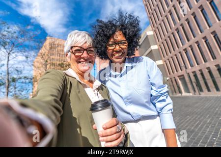 Vue frontale d'une femme d'affaires caucasienne mature et latine prenant un selfie à l'extérieur Banque D'Images