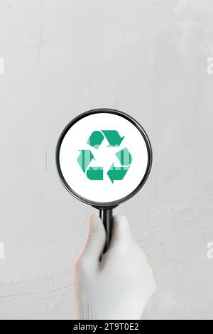 La main d'un employé tient une loupe pour inspecter les matériaux ou les déchets à recycler. Banque D'Images