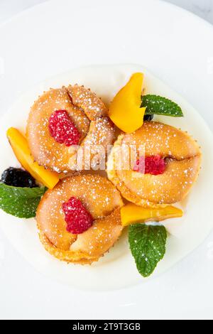 muffins à la pêche, framboise, baies noires et menthe recouverts de sucre en poudre, vue de dessus Banque D'Images