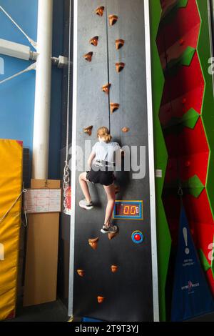 Neuf ans fille / âge 9 ans enfant sur un mur d'escalade intérieur, avec corde de sécurité en cas de chute, dans un centre sportif. ROYAUME-UNI. (136) Banque D'Images