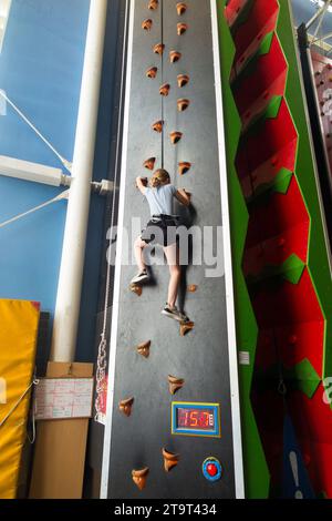 Neuf ans fille / âge 9 ans enfant sur un mur d'escalade intérieur, avec corde de sécurité en cas de chute, dans un centre sportif. ROYAUME-UNI. (136) Banque D'Images