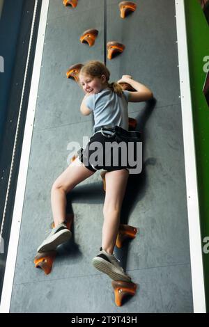 Neuf ans fille / âge 9 ans enfant sur un mur d'escalade intérieur, avec corde de sécurité en cas de chute, dans un centre sportif. ROYAUME-UNI. (136) Banque D'Images