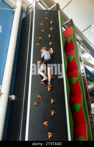 Neuf ans fille / âge 9 ans enfant sur un mur d'escalade intérieur, avec corde de sécurité en cas de chute, dans un centre sportif. ROYAUME-UNI. (136) Banque D'Images