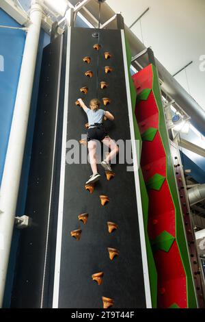 Neuf ans fille / âge 9 ans enfant sur un mur d'escalade intérieur, avec corde de sécurité en cas de chute, dans un centre sportif. ROYAUME-UNI. (136) Banque D'Images