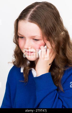Année 7 écolière enfant âgé de 11 ans / an enfant portant l'uniforme scolaire et Apple iphone téléphone intelligent mobile pour faire un appel téléphonique. ROYAUME-UNI. (136) Banque D'Images