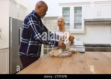 Divers couples seniors déballant les épiceries dans la cuisine. Style de vie, retraite, style de vie senior, shopping, convivialité et vie domestique, inchangés. Banque D'Images