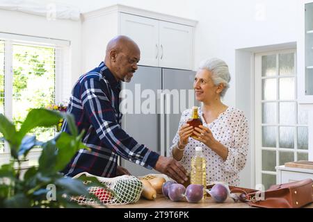 Divers couples seniors déballant les épiceries dans la cuisine. Style de vie, retraite, style de vie senior, shopping, convivialité et vie domestique, inchangés. Banque D'Images