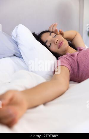 Femme biracial dormant couchée dans le lit à la maison ensoleillée. Mode de vie, temps libre et vie domestique, inchangés. Banque D'Images