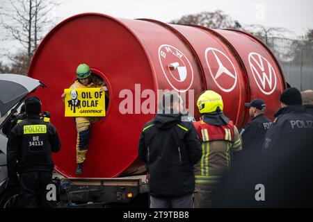 Berlin, Allemagne. 27 novembre 2023. Un militant de l’organisation environnementale Greenpeace sort d’un grand tonneau portant les logos des constructeurs automobiles BMW (de gauche à droite), Mercedes-Benz et Volkswagen devant la Chancellerie fédérale. La chancelière Scholz rencontre des représentants de l’industrie automobile pour discuter de la poursuite de l’expansion de la mobilité électrique sur les routes allemandes. Crédit : Hannes P Albert/dpa/Alamy Live News Banque D'Images