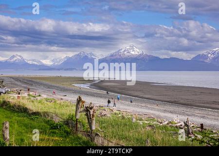 Les gens explorent la zone de marée le long de Bishops Beach à marée basse avec les montagnes Kachemak derrière à Homer, Alaska. Banque D'Images