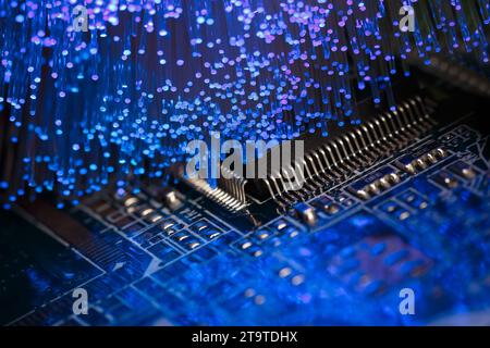 Macro-photographie d'une carte de circuit imprimé avec un processeur et des fibres optiques éclairant la carte Banque D'Images