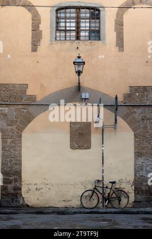 Vue sur la ville d'un vélo, lampadaire, vieux bâtiment en pierre et fenêtre avec barres métalliques dans le centre de Florence, Italie. Banque D'Images