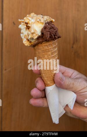 Une main serre un cône contenant des boules de délicieuse glace artisanale italienne, une délicatesse sucrée de renommée mondiale. Banque D'Images