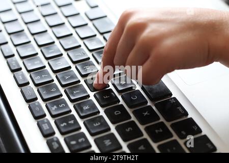 Vue générale d'un jeune enfant tapant avec un doigt sur un clavier d'ordinateur portable. Banque D'Images