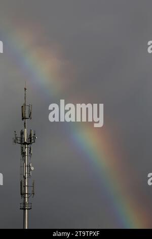 Un mât de téléphone portable et arc-en-ciel peuvent être vus. Banque D'Images