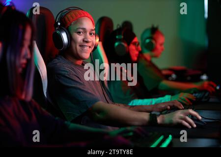 Portrait de femme afro-américaine jouant à des jeux vidéo et souriant à la caméra avec l'équipe pro de cybersports, espace de copie Banque D'Images