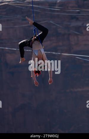 Une femme pend la tête en bas de son attache après être tombée de la ligne de mire au GGBY World Highline Festival près de Moab, Utah. Banque D'Images