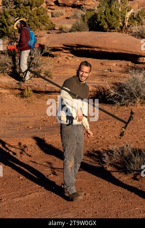 Un jeune homme s'entraîne avec un bâton de dragon de feu au GGBY Highlining Festival à Moab, Utah. Il roule le bâton le long de son bras. Habituellement, effectuer Banque D'Images