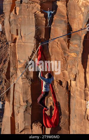 Une participante au GGBY World Highline Festival se produit sur les soies suspendues à une Highline. Moab, Utah. Un homme marche sur la ligne haute Be Banque D'Images