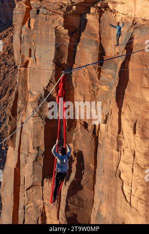 Une participante au GGBY World Highline Festival se produit sur les soies suspendues à une Highline. Moab, Utah. Un homme marche sur la ligne haute Be Banque D'Images