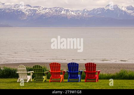 Chaises Adirondack colorées regardant vers la baie de Kachemak et les montagnes enneigées au-delà à Homer, Alaska. Banque D'Images