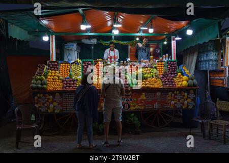 Afrique du Nord. Maroc. Marrakech. Un couple de touristes devant un stand de vendeur de jus de fruits à jemaa el fna la nuit Banque D'Images