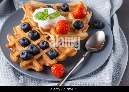 Délicieuses gaufres avec crème fouettée, fraises et myrtilles Banque D'Images
