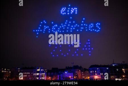 Berlin, Allemagne. 27 novembre 2023. Des drones lumineux survolent un stade dans un spectacle de drones organisé par Deutsche Umwelthilfe, formant les mots "a Peaceful 2024" dans le ciel. Le spectacle de drones DUH est destiné à montrer quelles alternatives il y a aux feux d'artifice le soir du nouvel an. Crédit : Monika Skolimowska/dpa/Alamy Live News Banque D'Images