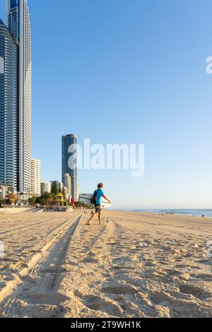 Surfers Paradise Australia - septembre 23 2023 ; image floue d'un surfeur portant une planche sur la plage au premier plan et gratte-ciel de grande hauteur avec des bâtiments Banque D'Images