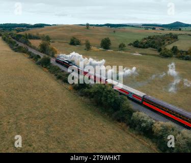 Vue aérienne d'un train circulant le long d'une voie ferrée, avec de la fumée sortant du moteur Banque D'Images