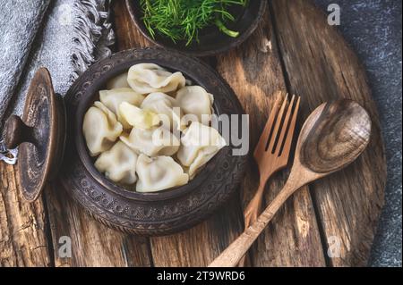 Boulettes de viande, boulettes russes maison dans un bol en argile moulé à la main et ustensiles en bois écologiques avec fourchette et cuillère. La fourchette et la cuillère en bois Banque D'Images