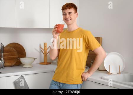 Jeune rousse buvant du jus dans la cuisine Banque D'Images