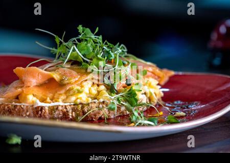 Fromage crémeux grillé garni d'œufs brouillés et de saumon fumé de près. Banque D'Images