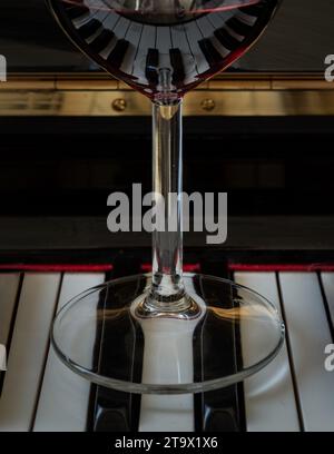 Verre de vin rouge sur clavier de piano. Concept de musique et de vin, espace de copie, mise au point sélective. Banque D'Images