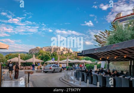 Herakleidon St dans le quartier de Thissio, Athènes, Grèce, avec des gens dans le café-terrasse et la colline de l'Acropole en arrière-plan. Banque D'Images