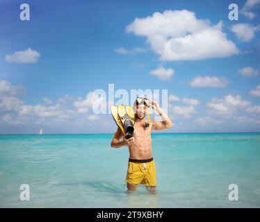 Homme avec palmes de plongée et masque debout dans la mer bleue des Caraïbes Banque D'Images
